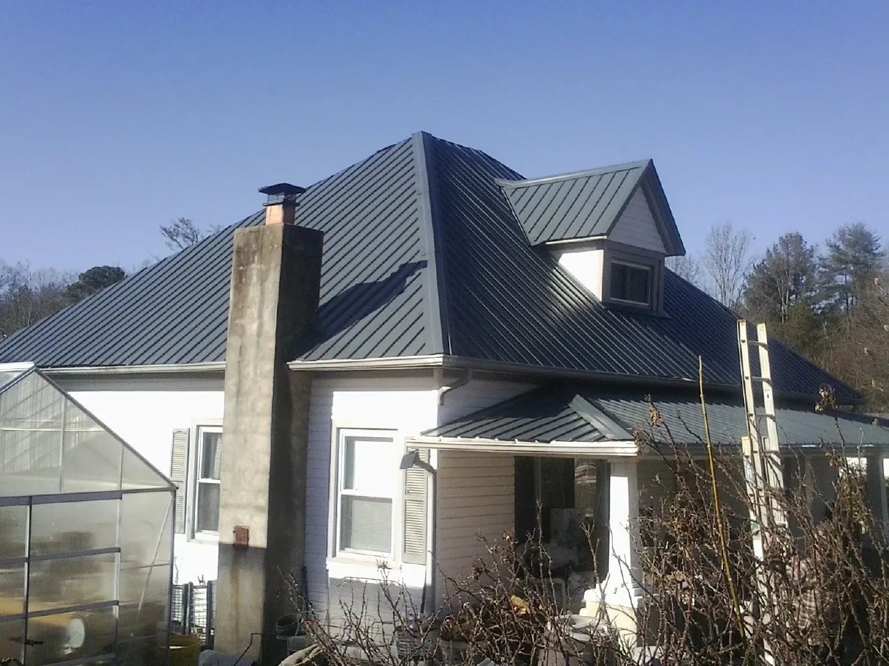 Dark blue standing seam metal roof on a white farmhouse with dormer — Slate & Tile Roof Repair by Roofing Brothers in Midland Park