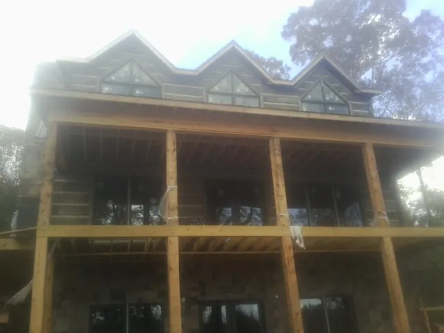 Dormers and porch framing on a large log home under construction — Roof Coating work by our crew in Midland Park