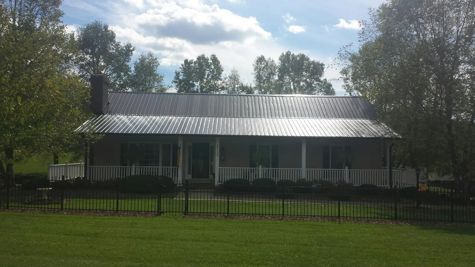 Gray metal roof on a brick ranch with a full width front porch — Gutter Guard Installation work by our crew in Midland Park