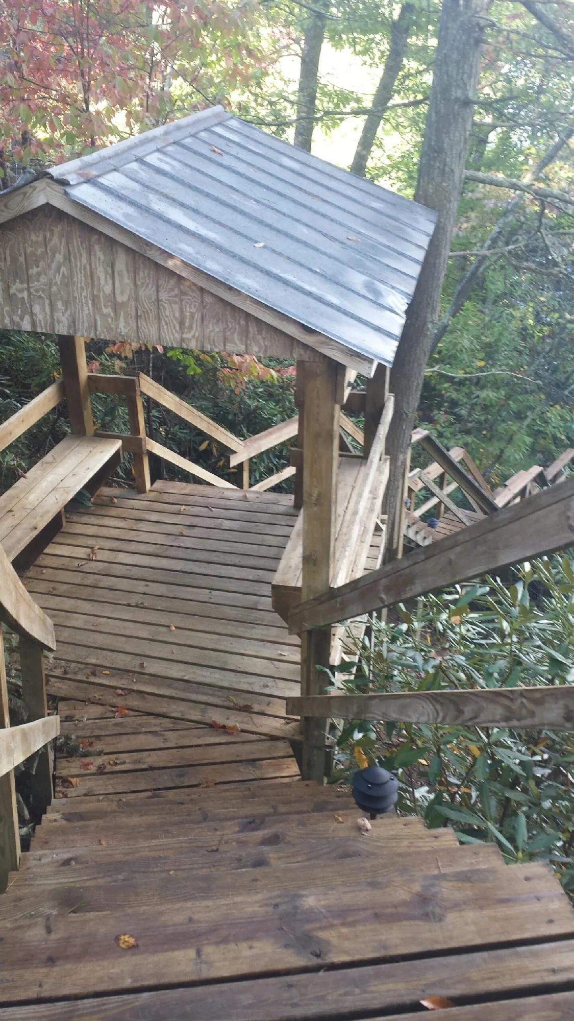 Metal roofed shelter over wooden steps on a wooded walkway — Skylight Repair & Installation work by our crew in Midland Park
