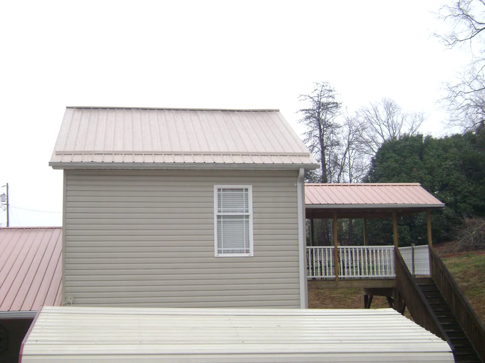 Tan metal roofs on a two story addition and attached porch, from a Roof Replacement job in Midland Park