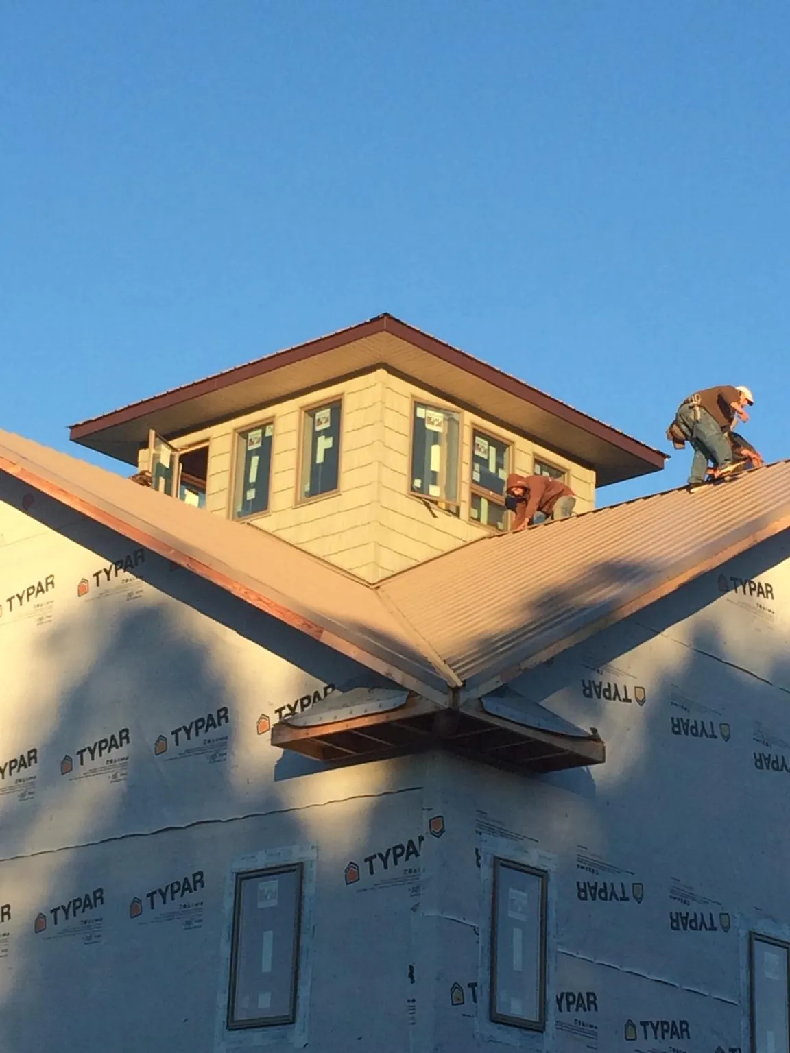 Roofers working around a rooftop cupola on a new metal roof at sunset — Roof Waterproofing in Midland Park by Roofing Brothers